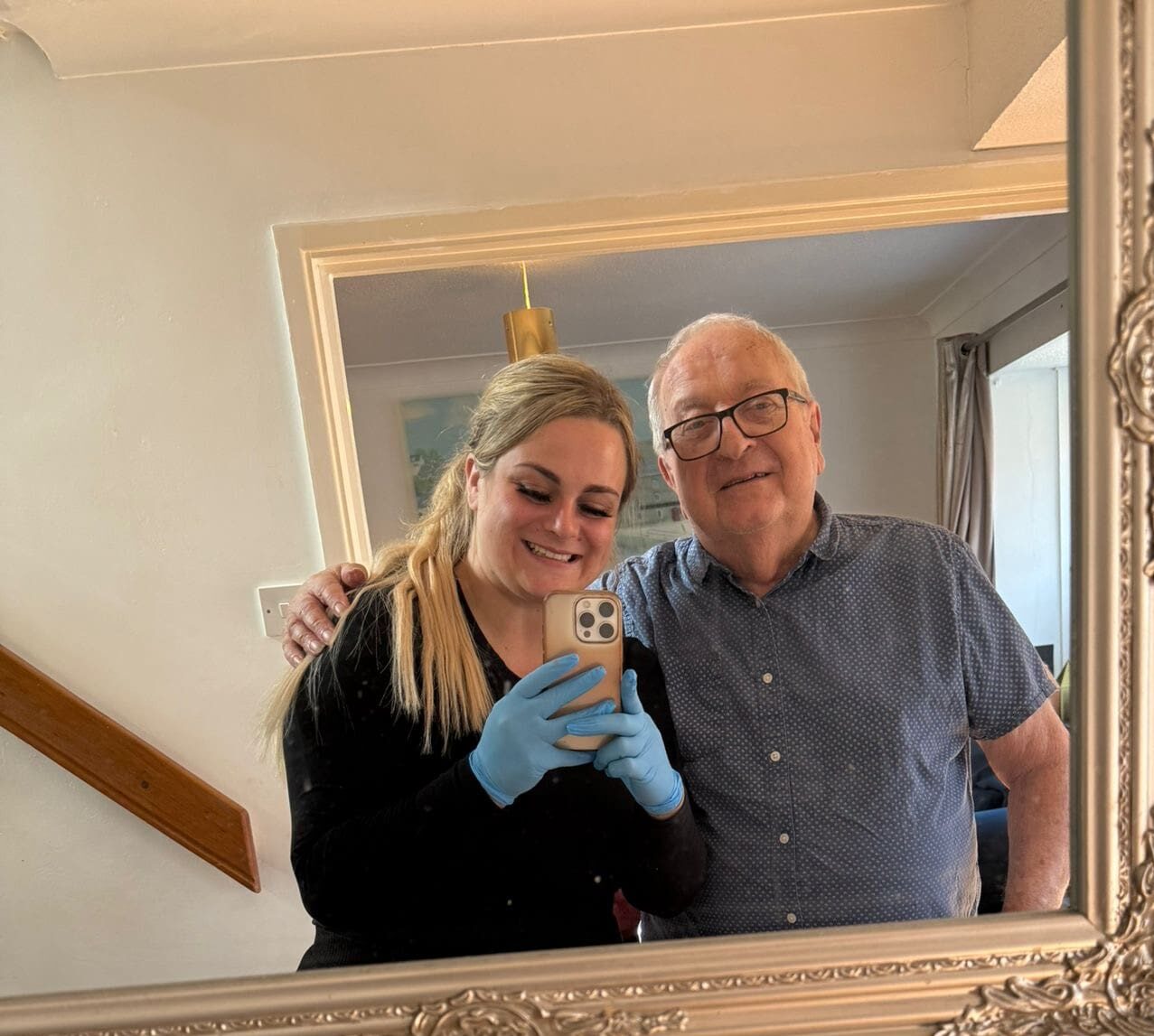 A caregiver smiling with an elderly man in a cozy living room, reflecting the supportive relationship fostered through compassionate care.