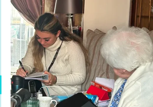 A caregiver provides attentive support to an elderly client during a care service review, showcasing compassion and dedication in a cozy home setting.
